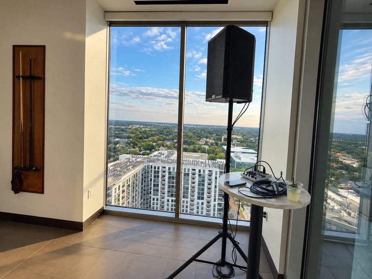 A speaker, compact mixer and wireless microphone arranged beside a high-rise window.
