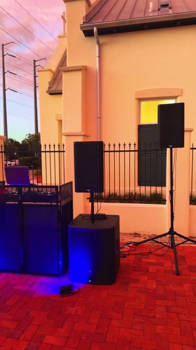 A short walk around an outdoor DJ booth with speakers and colored lighting.