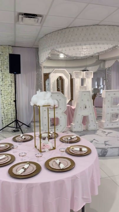 A decorated event room with speakers on stands and tables ready for guests.