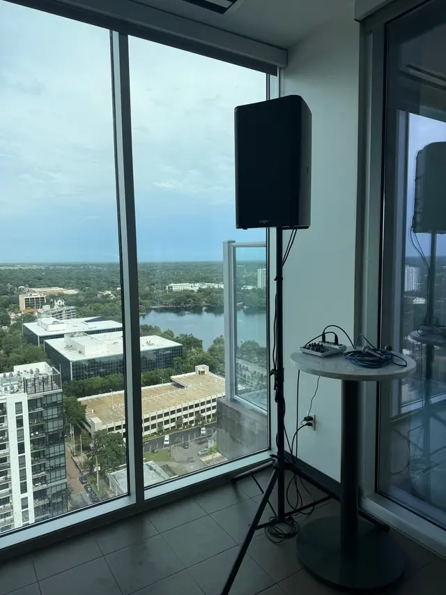 Compact speaker and mixer setup beside a high-rise window